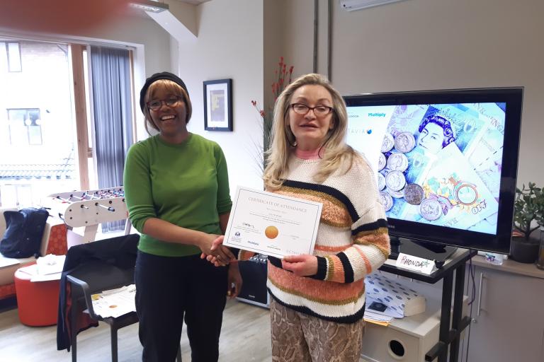 Evelyn is presented with her completion certificate by the course tutor