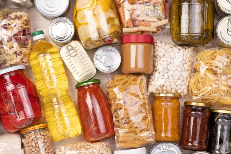 A collection of non perishable and essential food items including packets of pasta and tinned foods