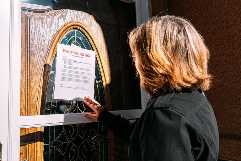 A woman sees an eviction notice on the door of a house
