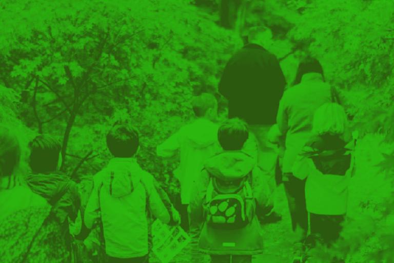 A photo of children walking through a wooded area. The photo is covered with a green tint.