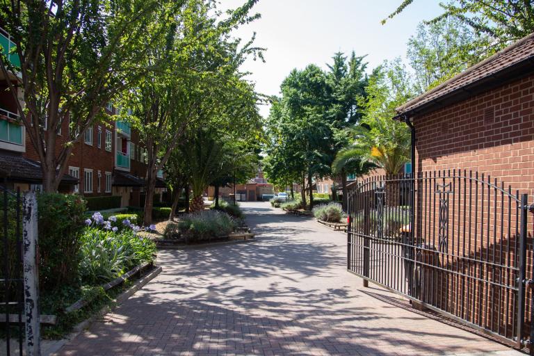 Picture of gate leading onto estate with a building and green trees and garden