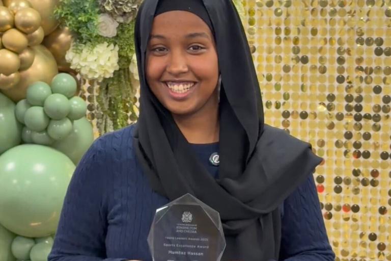 A Winner of young leaders award holds up her trophy 