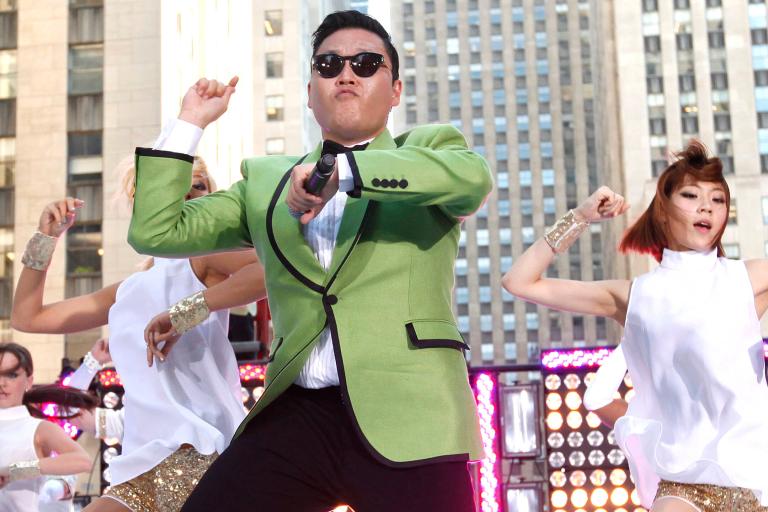 gangnam Style performance with male dancer in green jacket with dancers in white behind
