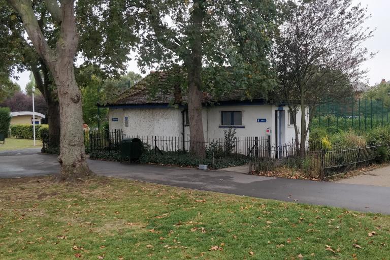 Small white building in a park.