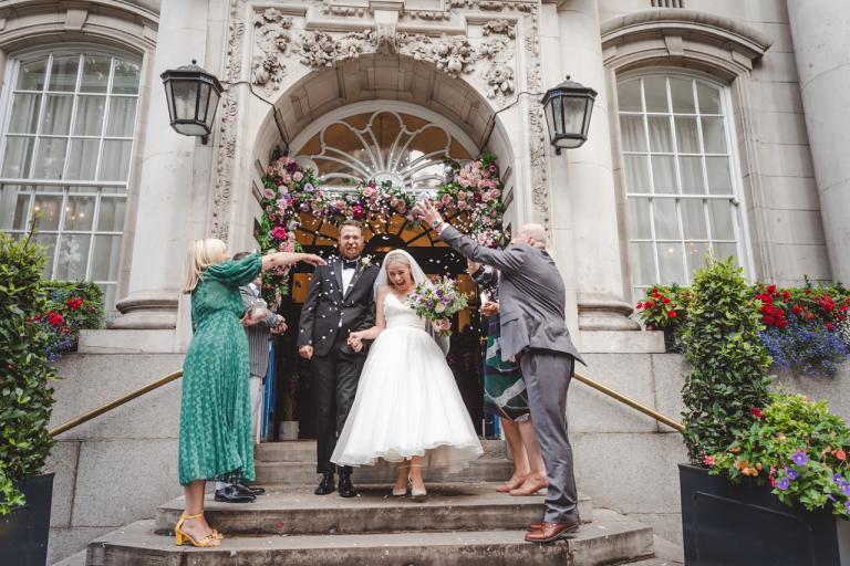 A couple walking down the steps whilst people throw confetti