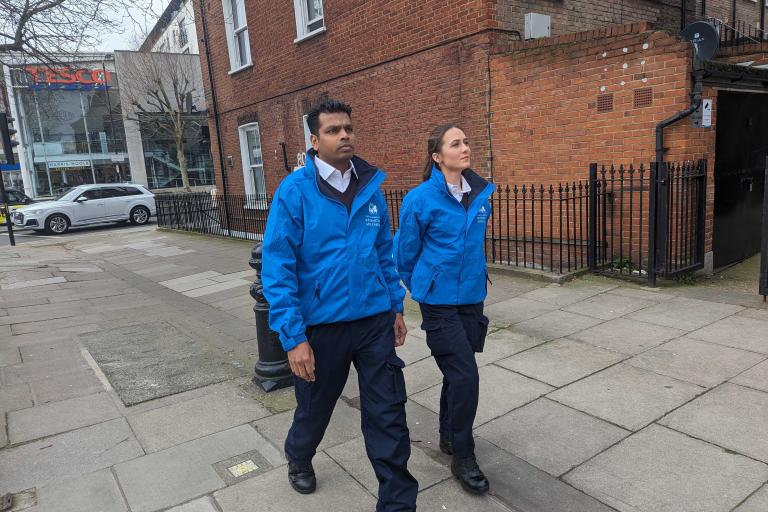One male street enforcement officer and one female street enforcement officer walking side by side in blue uniform in Kensington.