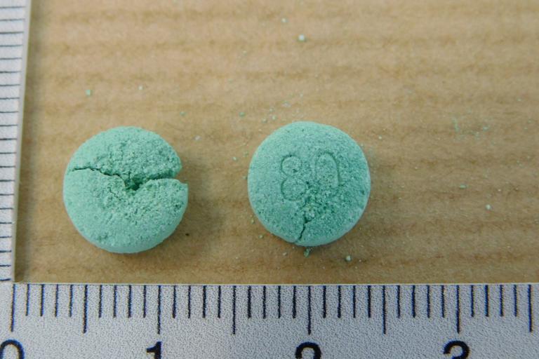 image of green pill with ruler to show size