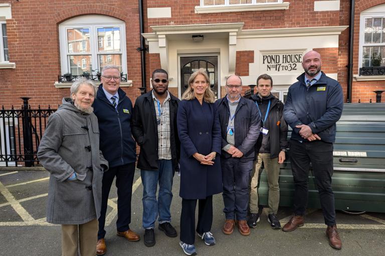 7 people standing in front of a red brick building