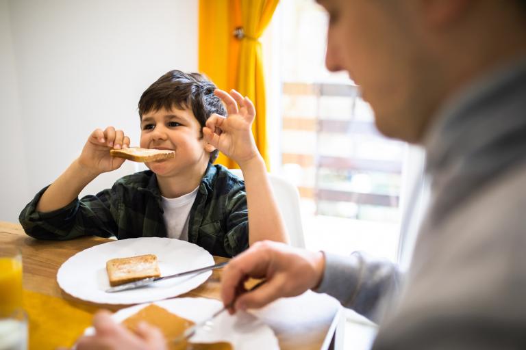 A child eats toast with his parent