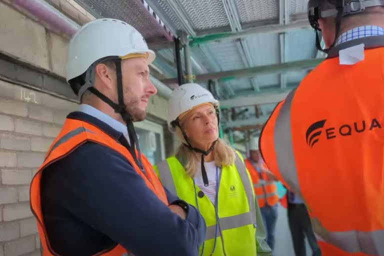 man and women standing on scaffolding wearing high visibility jackets and hard hats 