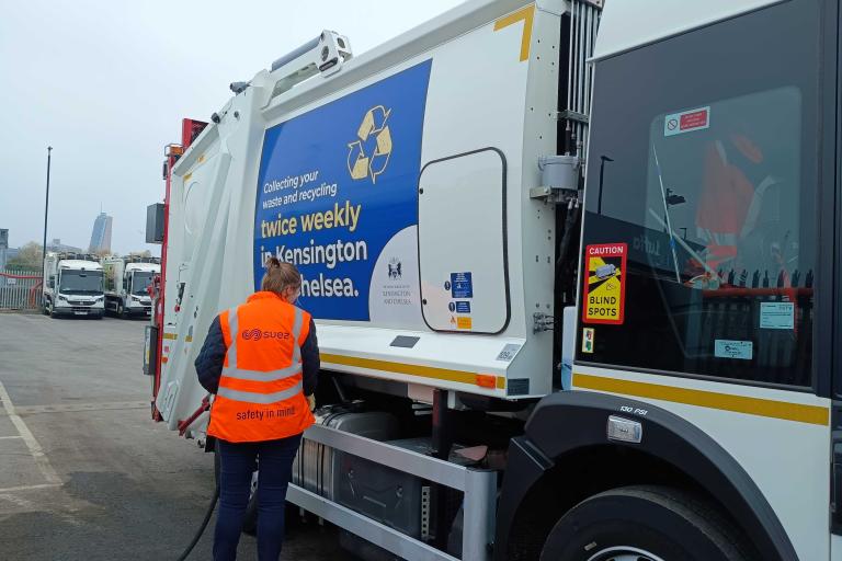 Female refuse worker refilling a waste collection vehicle with biofuel