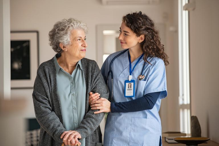 A care worker supporting an elderly person walking