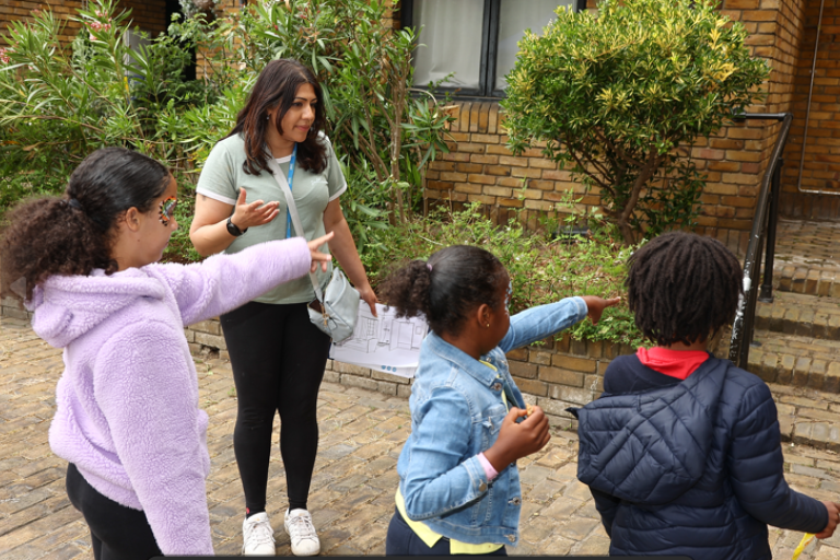 woman outside flats organising an activity with three small children