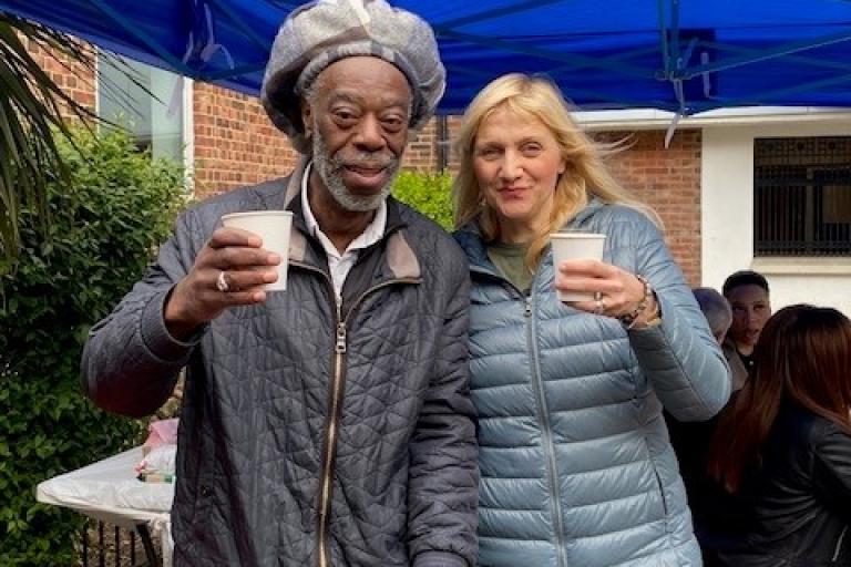 Two neighbours enjoy a chat while drinking a hot beverage