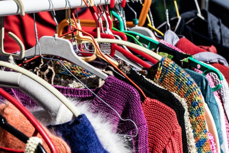 Colourful sweaters hanging on rail