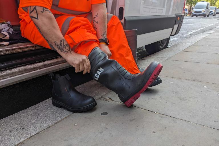 A member of the grime busters street cleaning team sat in a van butting on wellington boots ahead of starting work