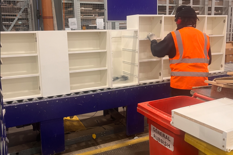man in orange high vis jacket assembling a shelving unit on assembly line