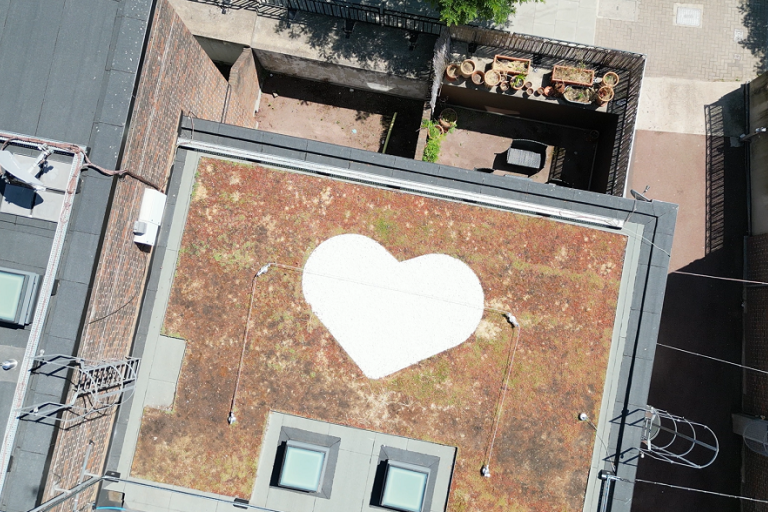 Drone shot looking down on the grenfell heart motif on the roof of camelford court