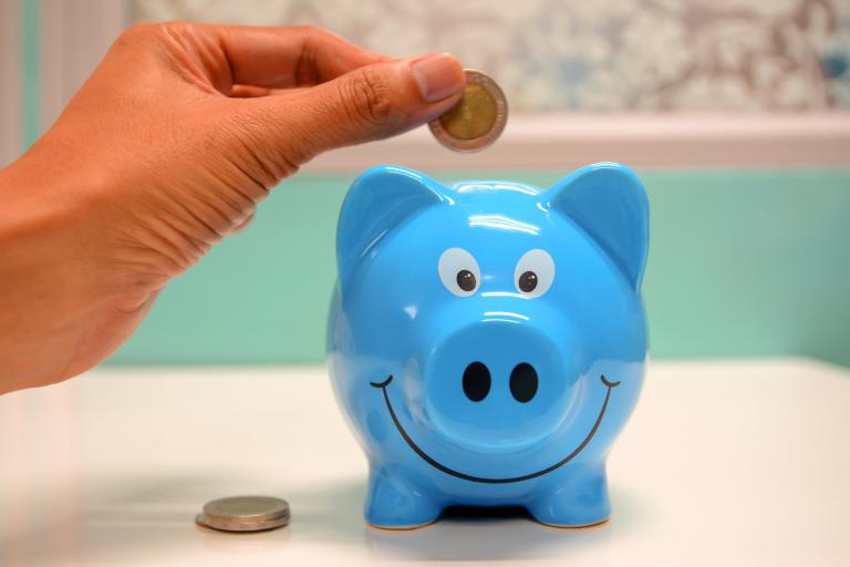 someone putting coins in a piggy bank