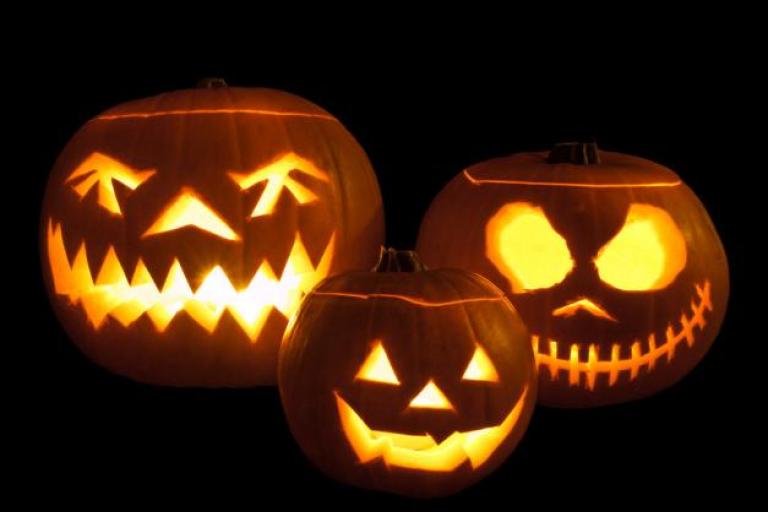 three carved pumpkins witth candles in