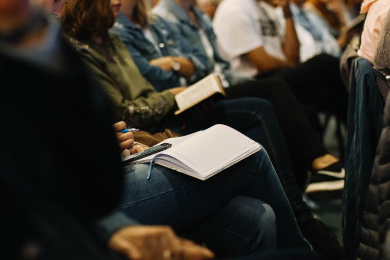 A group of people in a seminar holding notebooks