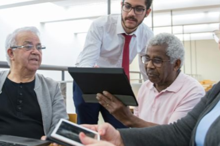 Three men and one lady looking at electronic device