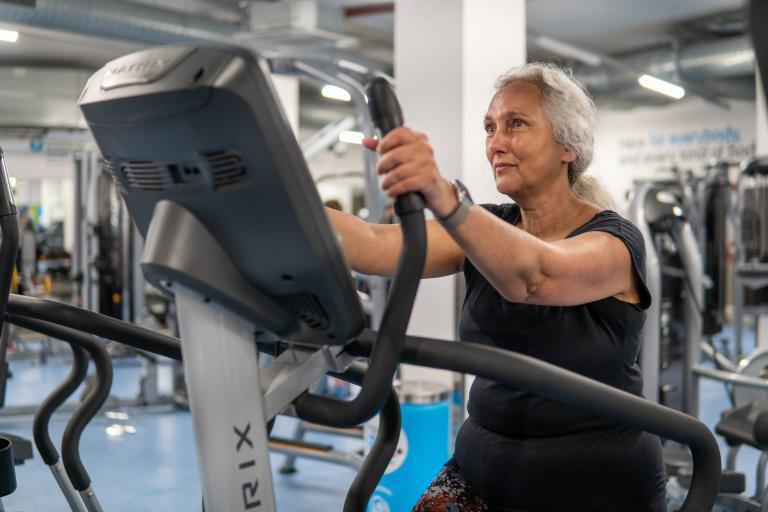 A grey haired older woman on gym machine