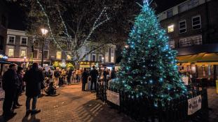 A Christmas tree in a pedestrianised square with people around it