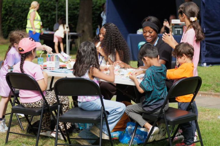 table on grass lawn with 5 small children doing arts and crafts
