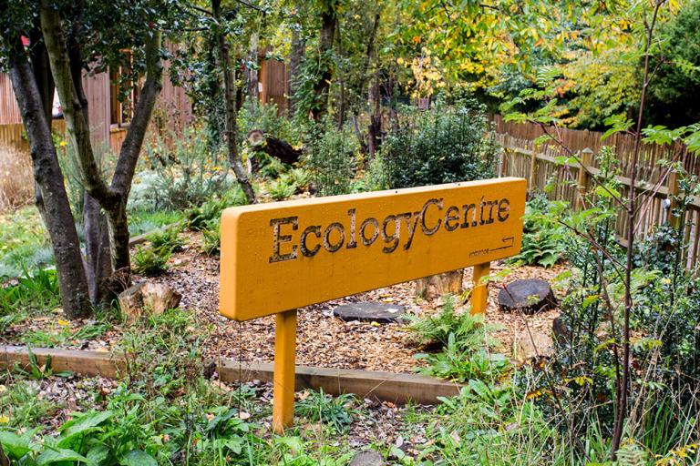 Sign post at the entrance saying The Ecology Centre shown in the park
