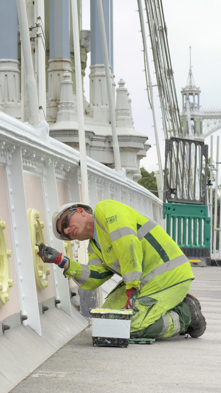 A worker paints Albert Bridge