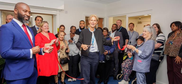 A group of staff and residents gather in the new office as Councillor McVeigh cuts the ribbon