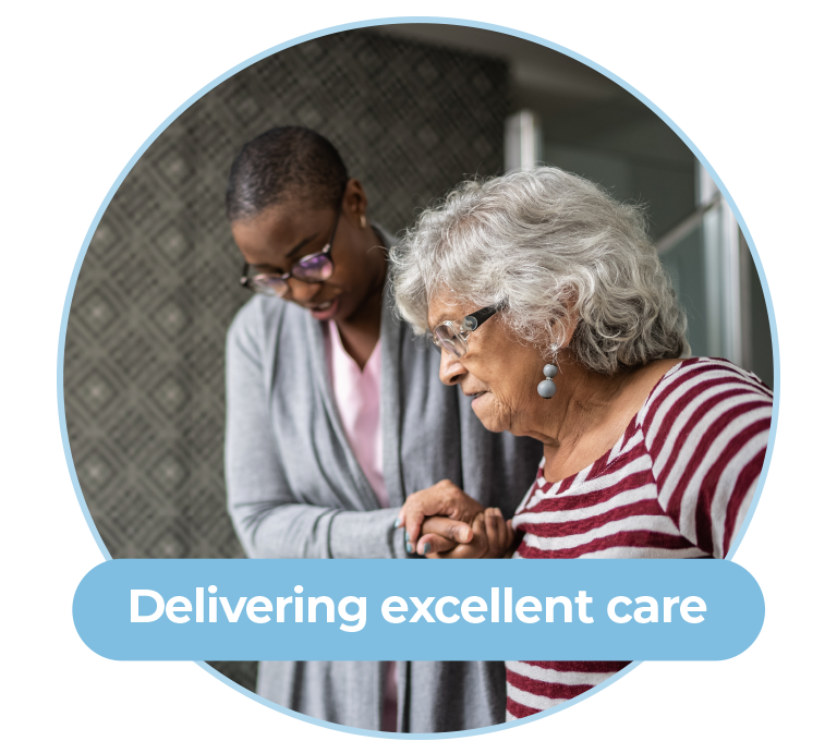 A graphic of a large circle with a photo inside. The circle has a light blue border. The photo is of a young black woman helping an older white women by holding her hand whilst walking. This photo is the background of the graphic. On top of the photo is the words “Delivering excellent care” in white text on a light blue background. 