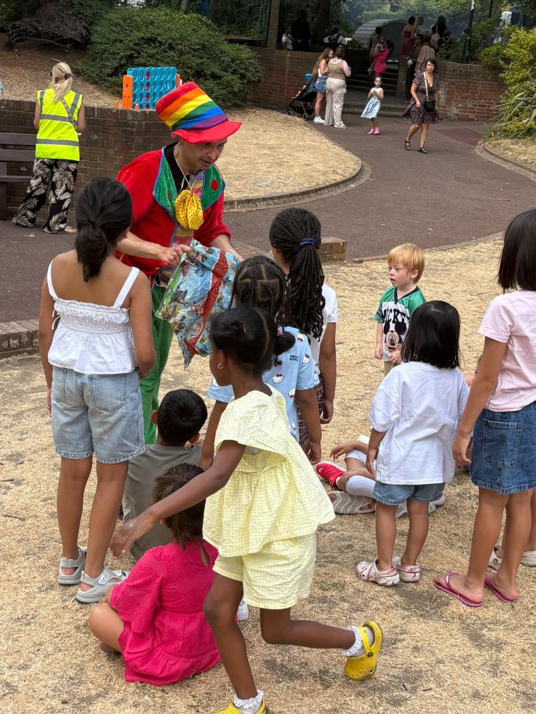 childrens entertainer with rainbow hat presenting his show infront of an audience of small children