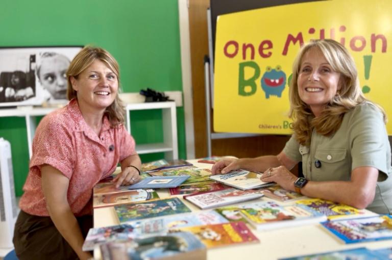Liberty Venn and Cllr Catherine Faulks sit at a table smiling, surrounded by books. 