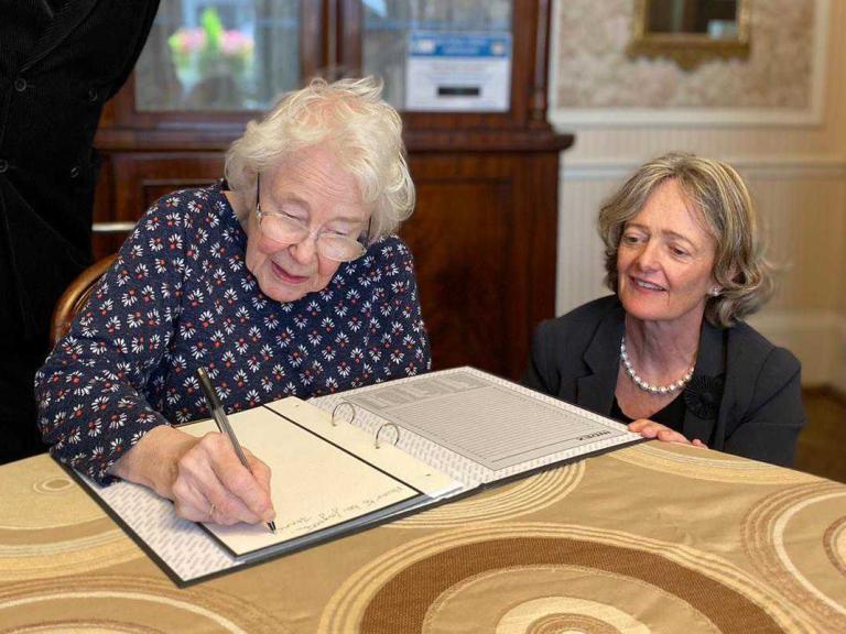 A sheltered housing resident signs a book of condolence following the passing of Queen Elizabeth II