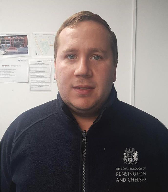 Image of white man with blue eyes and blonde hair smiling at the camera wearing a navy blue fleece with a Council logo on it