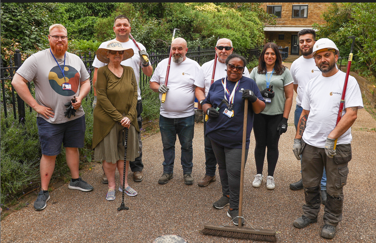 9 people standing with gardening utensils posing 