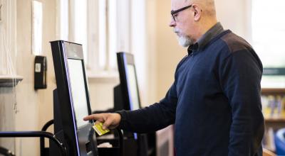 A man using the self-service screens in the library