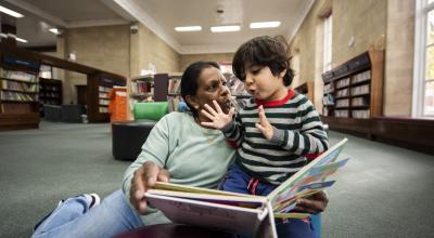 A woman reading a book to a young boy in a library.