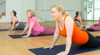 Three women on Yoga mats facing towards the floor pushing up on their hands so that their arms are straight.