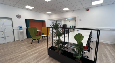 A large meeting room with a bank of desks that seat six people.