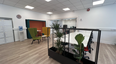 A large meeting room with a bank of desks that seat six people. 