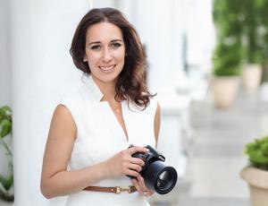 Neli Prahova dressed in cream sleeveless top holding a DSLR camera