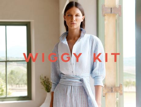 Woman in white shirt and grey skirt standing in a sunlit room