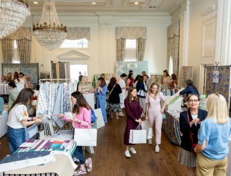 Shows a fashion event with rails of clothes standing in a large ornate hall