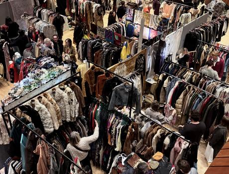 A selection of frocks, dresses and different vintage clothes hanging from clothing racks.