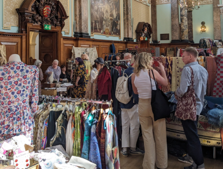 Two people gather around a selection of frocks.